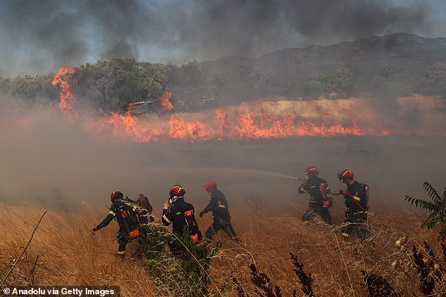 Flames and smoke rise from burning trees while firefighters continue their efforts to extinguish the fire that broke out in the forest area near the Komotini, Greece on August 10, 2025