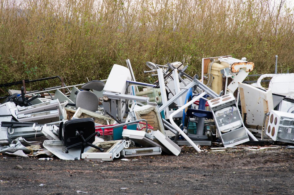 Pile of discarded appliances and furniture at a rubbish dump.