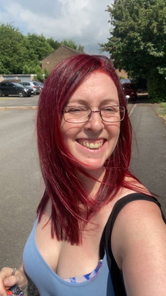 Woman with red hair smiling outdoors.