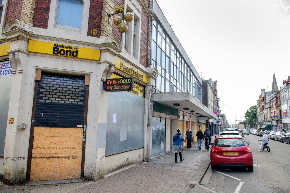 Boarded-up shops and a closed pawnbroker on a city street.