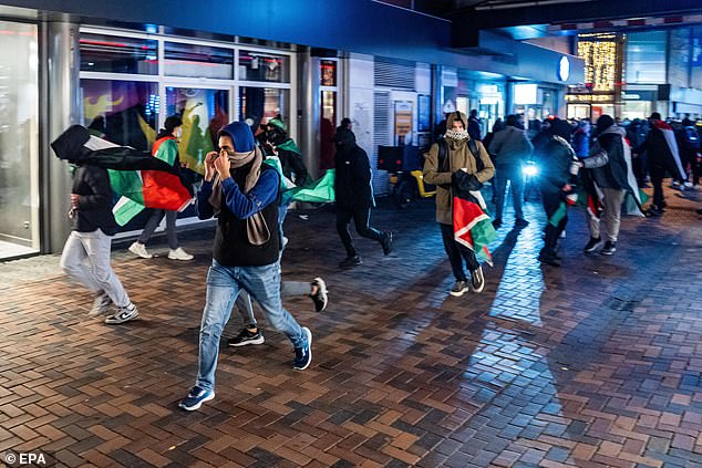 A masked mob, some carrying Palestinian flags, are seen running riot through the streets of Amsterdam in November
