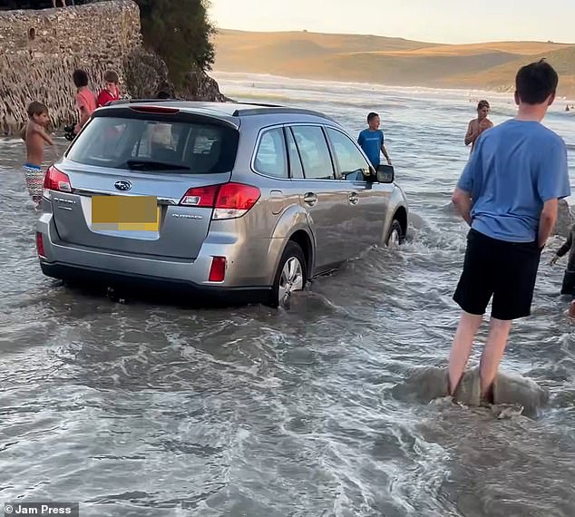Motorists parked on the sand at a popular UK beach could not believe their eyes when they discovered a rising tide had swamped the area - leaving their vehicles partially submerged in the sea
