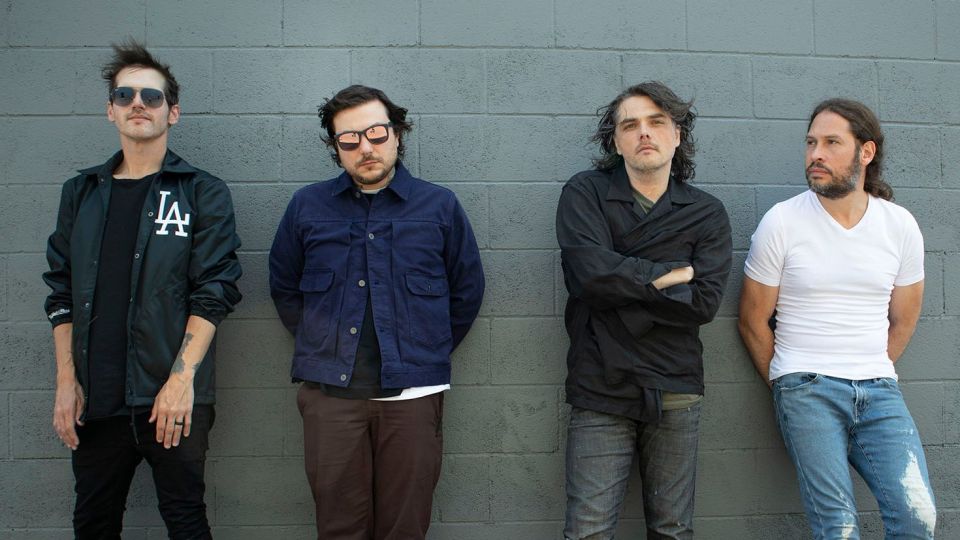 My Chemical Romance band members posing against a wall.