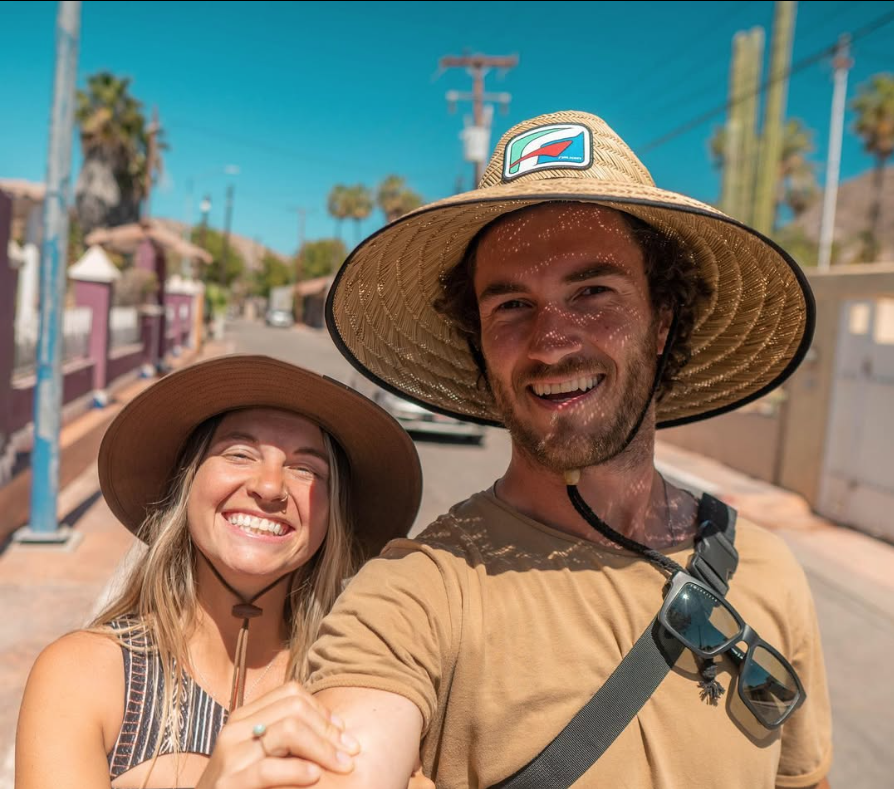 Selfie of a smiling couple wearing hats outdoors.