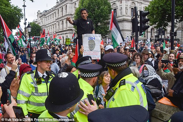 A protester holds up a '1984' sign criticising the Met Police as officers arrest a pair of protesters in Whitehall on July 19 who were holding placards stating 'Palestine Action are not the terrorists'