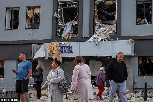 People stand at the site of a building housing the local branch of the British Council after it was hit during Russian missile and drone strikes