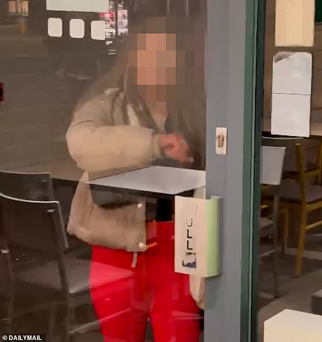 Pictured: The 14-year-old ringleader, who claims she is untouchable attempting to smash the Subway door