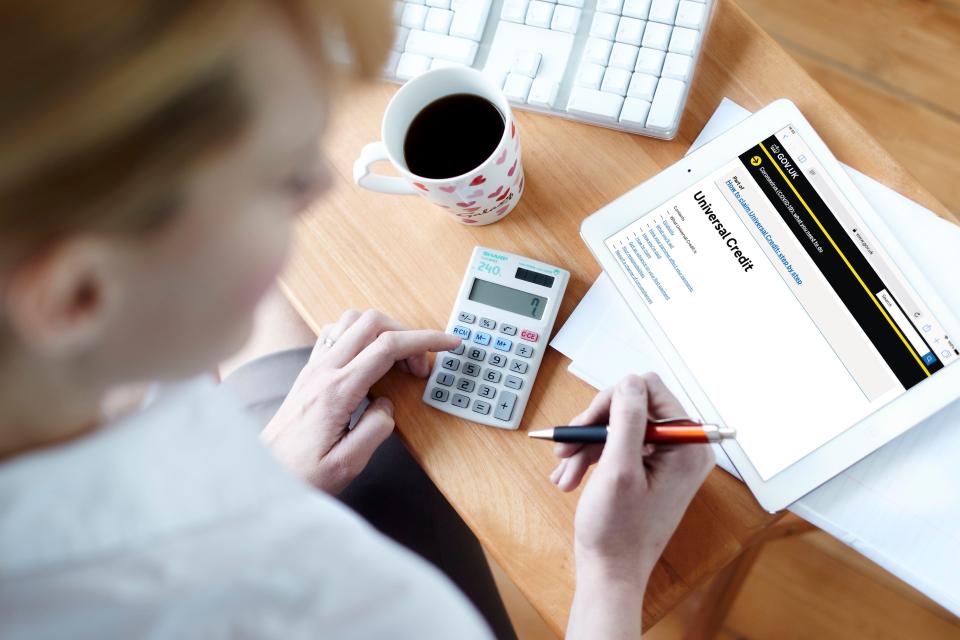Woman using calculator and tablet to apply for Universal Credit.