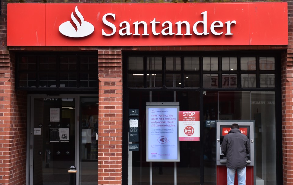 A man uses an ATM outside a Santander bank branch.