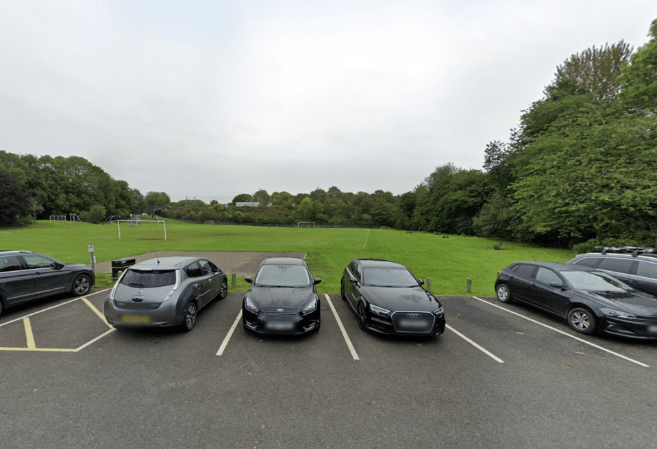 Cars parked near a playing field.
