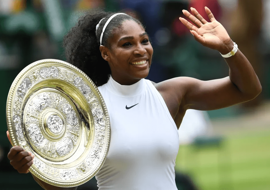 Serena Williams holding a trophy and waving.
