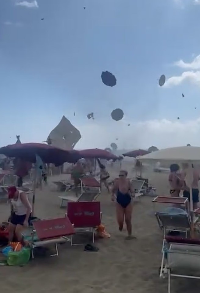 Beachgoers fleeing a tornado that lifts beach umbrellas into the air.
