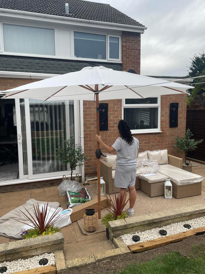 Person assembling patio furniture and umbrella.