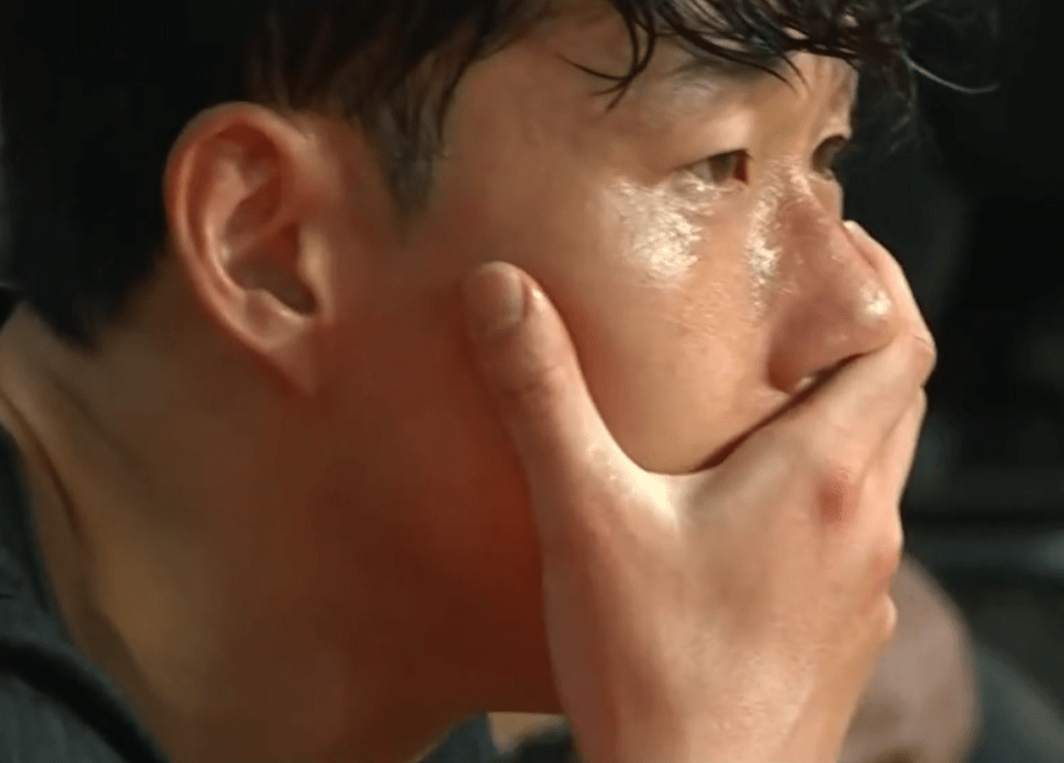 A man crying, covering his mouth with his hand.