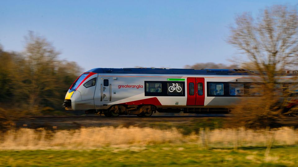 Greater Anglia Flirt train speeding past countryside.
