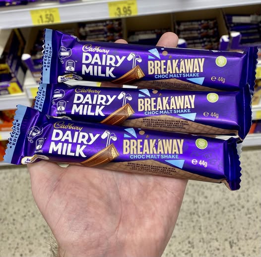 Hand holding three Cadbury Dairy Milk Breakaway Choc Malt Shake bars.