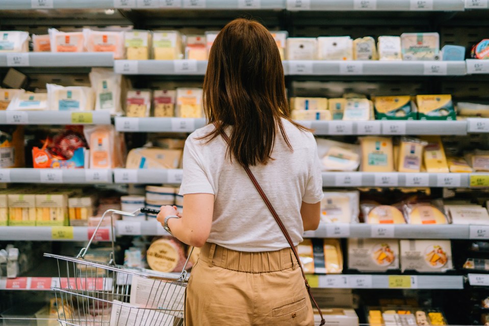 Woman shopping for cheese in a supermarket.
