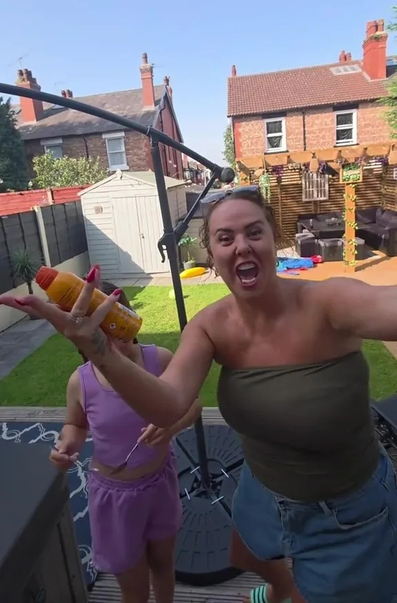 Woman applying sunscreen to child in backyard.