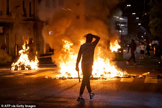 A young person walks past fires in a street, in Lausanne, on August 25, 2025