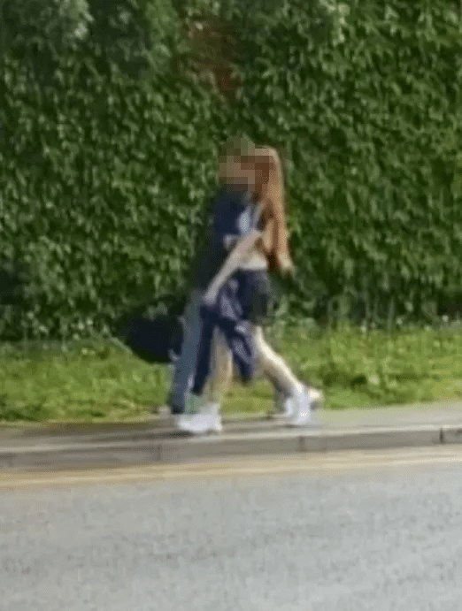 Two people walking down a sidewalk.