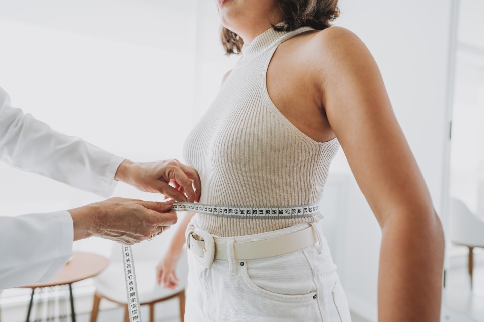 Doctor measuring a woman's waist with a tape measure.