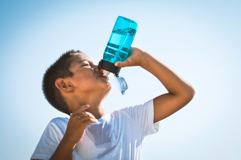 Boy drinking water from a blue bottle.
