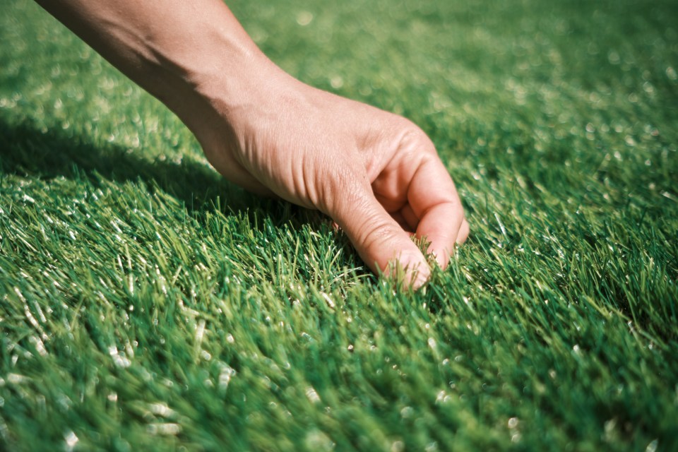 Hand touching artificial grass.