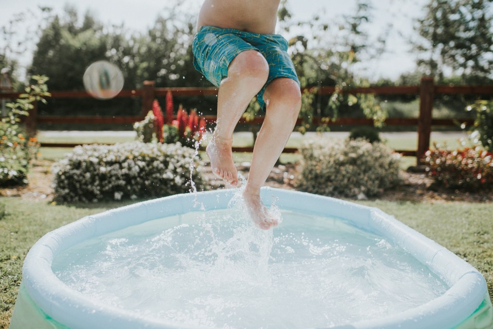 Boy jumping into a paddling pool.