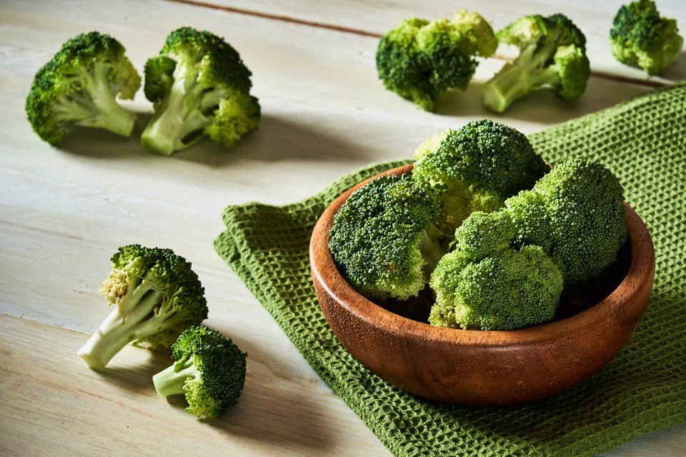 Raw broccoli florets in a wooden bowl.