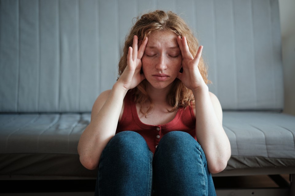 Woman holding her head in her hands, appearing stressed.
