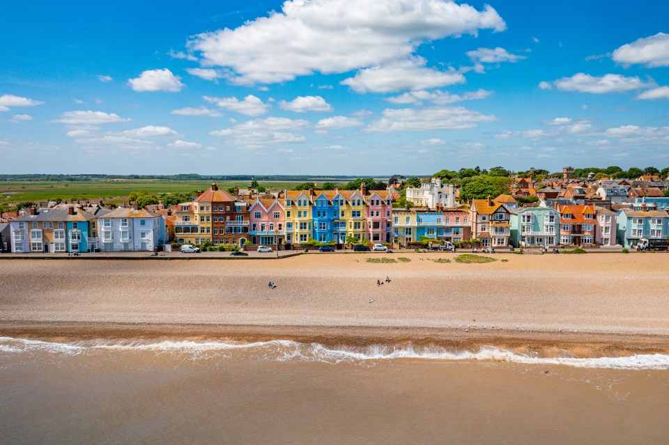 Aerial view of Aldeburgh Beachfront in Suffolk, with colorful houses and people on the beach.