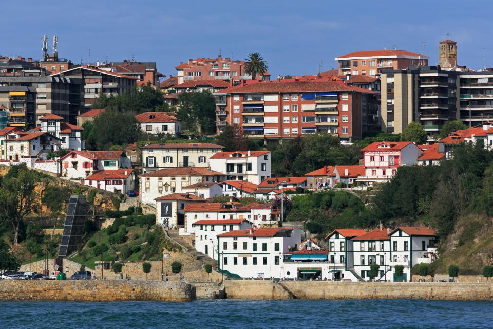 View of Getxo, Bilbao, Spain, showing buildings on a hillside overlooking the water.