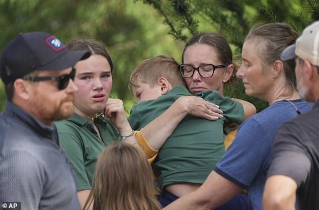 Pictured: Parents comforting their children following the deadly shooting on Wednesday