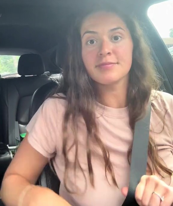 Woman in a car adjusting her seatbelt.