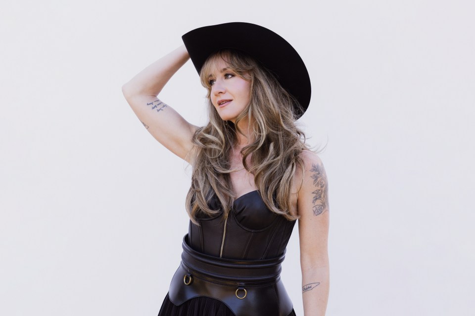 Margo Price wearing a black hat and corset.