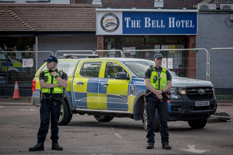 Two police officers stand guard near The Bell Hotel in Epping, UK.