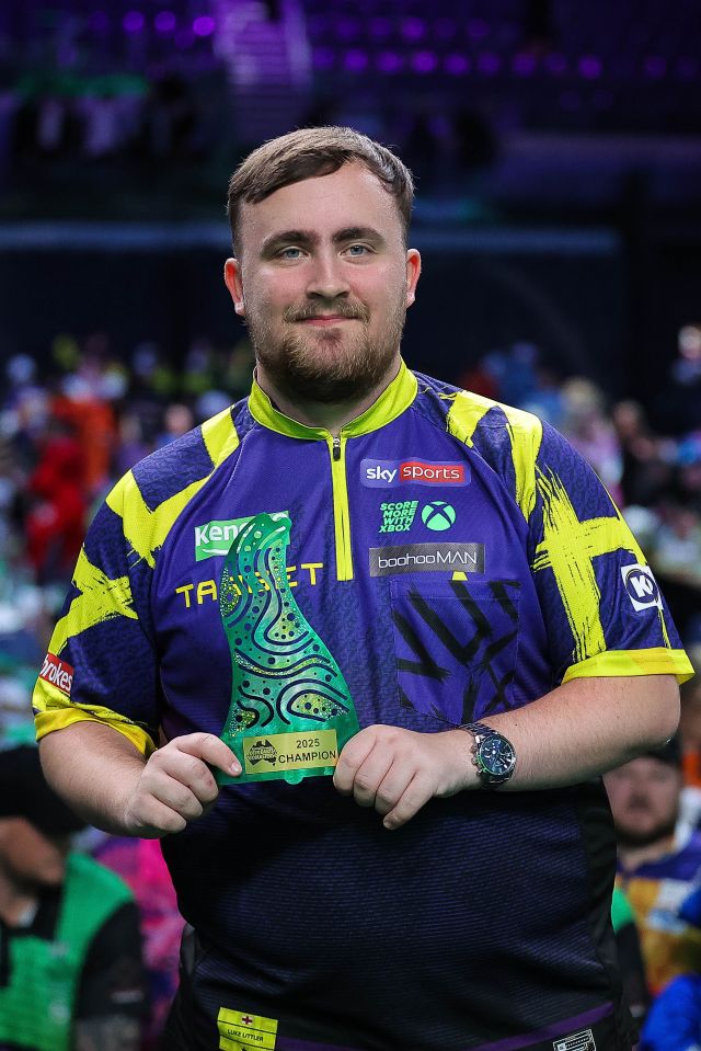 Luke Littler holding the 2025 Australian Darts Masters champion trophy.