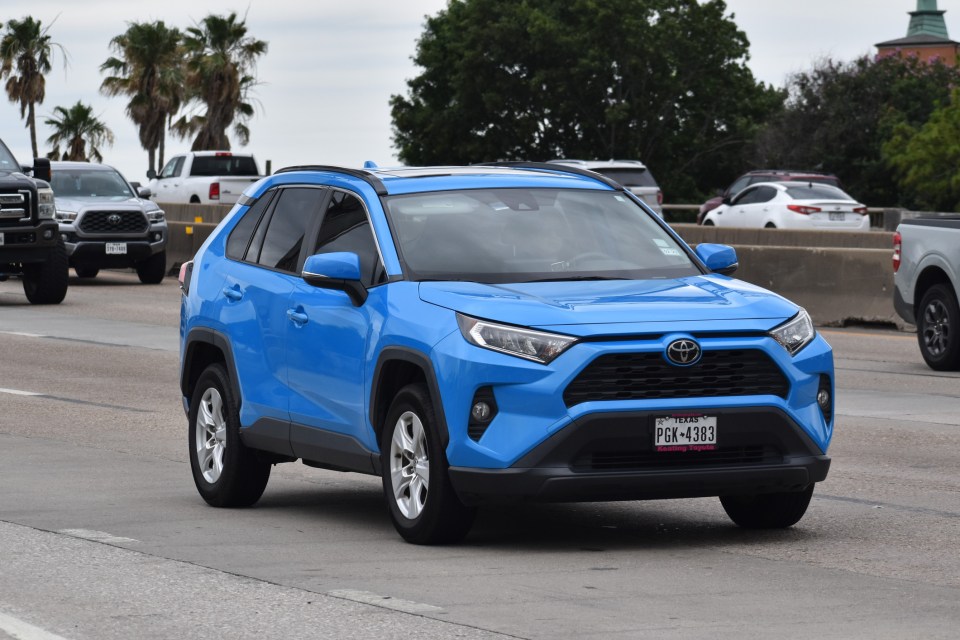 Blue Toyota RAV4 driving on a highway.