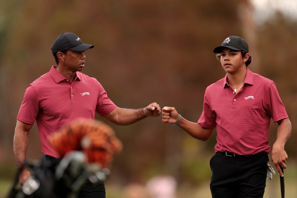 Tiger Woods and his son Charlie Woods fist-bumping on a golf course.