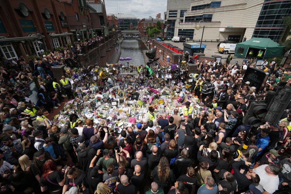 BIRMINGHAM, ENGLAND - JULY 30: fans view tributes to the late Ozzy Osbourne from fans at Black Sabbath Bench and Bridge as his funeral cortege travels through his home city of Birmingham on July 30, 2025 in Birmingham, England. The Black Sabbath frontman passed away on July 22nd at the age of 76. His death occurred just a little over two weeks after his final live performance at the 'Back to the Beginning' concert in his hometown of Birmingham. (Photo by Christopher Furlong/Getty Images)