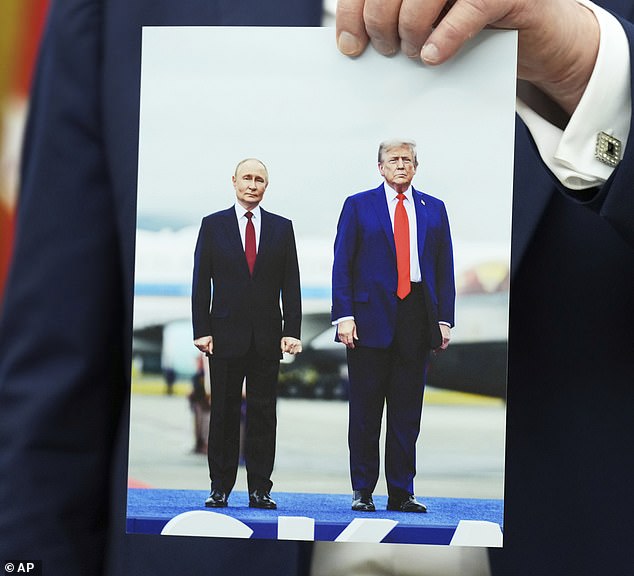 US President Donald Trump holds a photo of him with Russian President Vladimir Putin that he said was sent to him by Putin