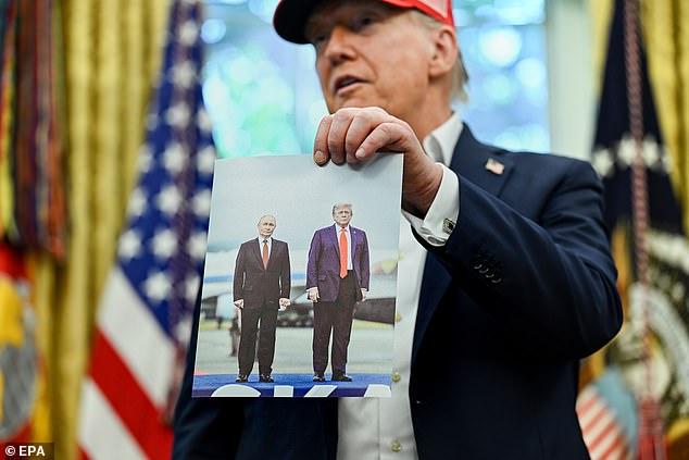US President Donald Trump holds a photo of him with Russian President Vladimir Putin in Alaska