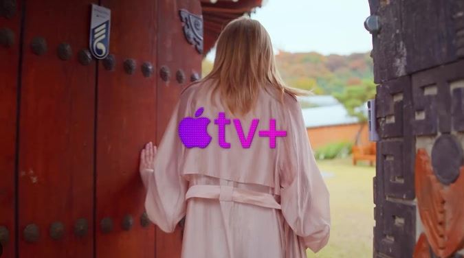 Woman with Apple TV+ logo on her back walking through a gate.