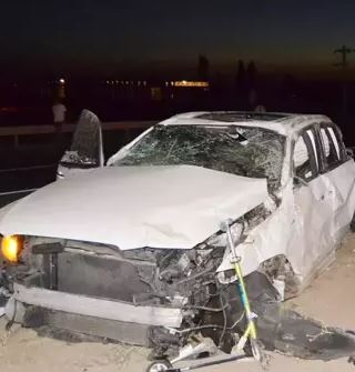 A wrecked car on the side of a road at night.