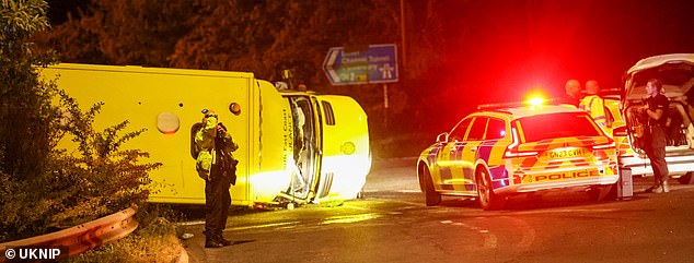 Two crew members inside the toppled and smashed-up ambulance (pictured) were rushed to hospital