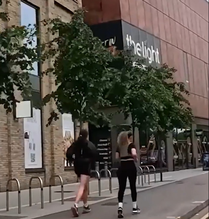 Two people walking past The Light.