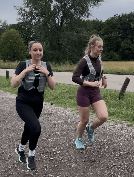 Two women jogging on a gravel path.