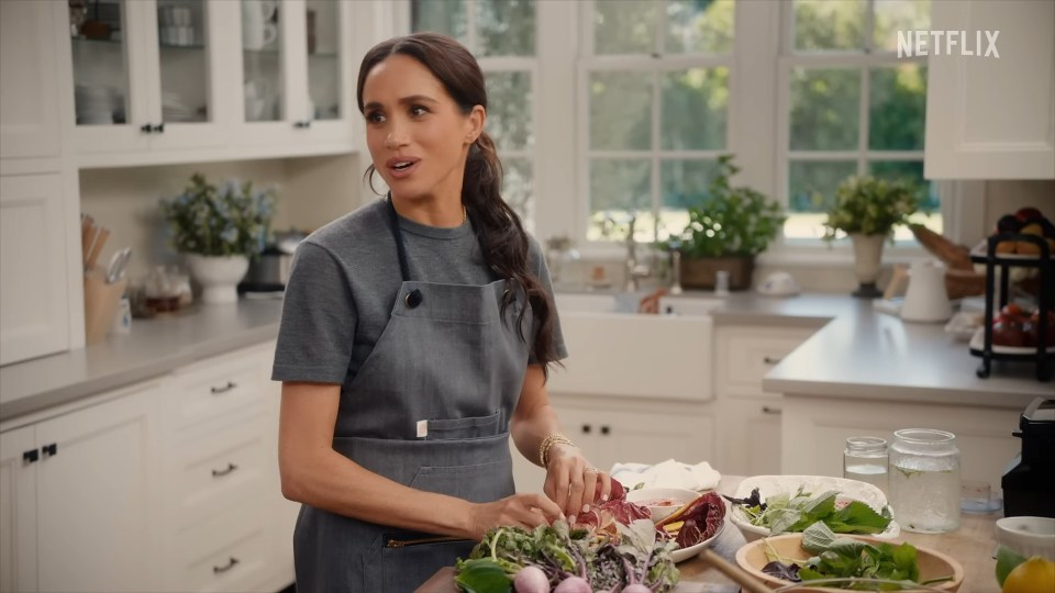 Meghan Markle cooking with Chef Roy Choi in a kitchen.