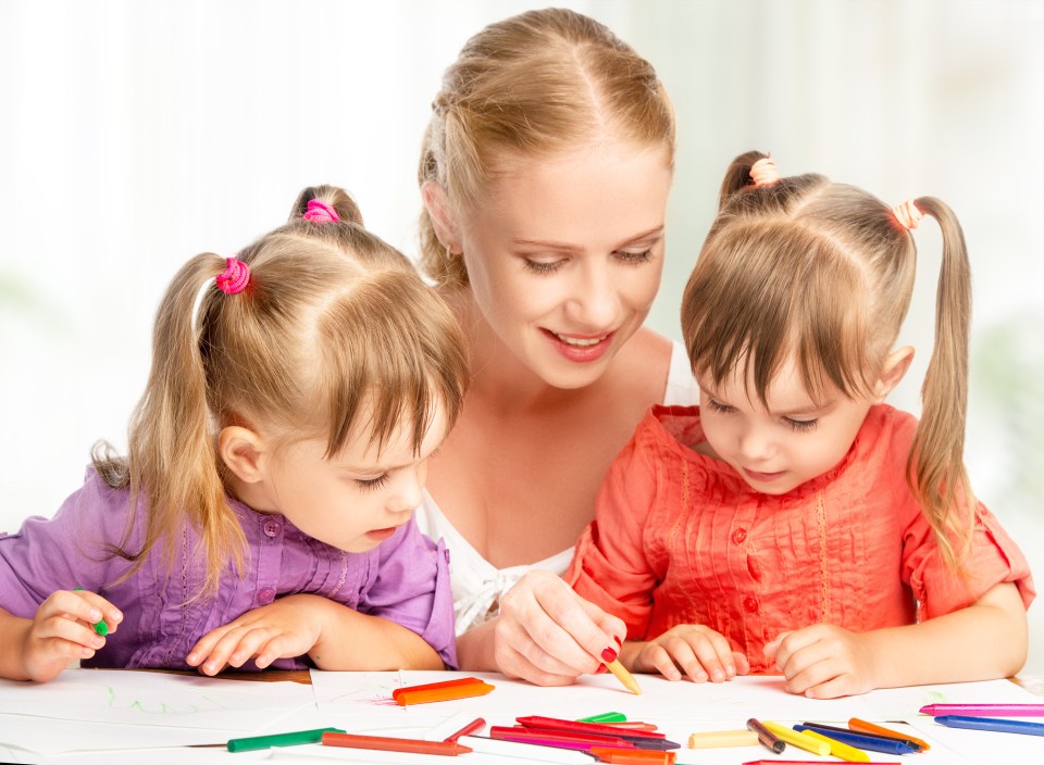 Mother and twin daughters drawing together.