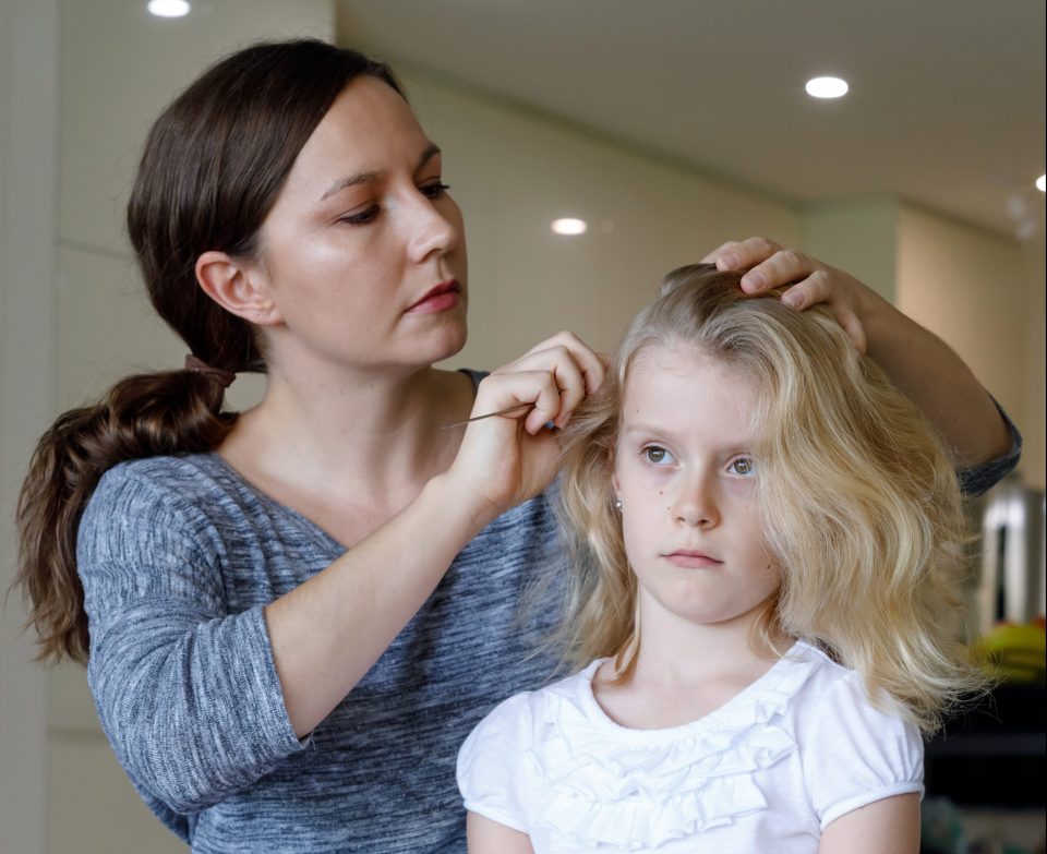 Mother checking daughter's hair for lice.